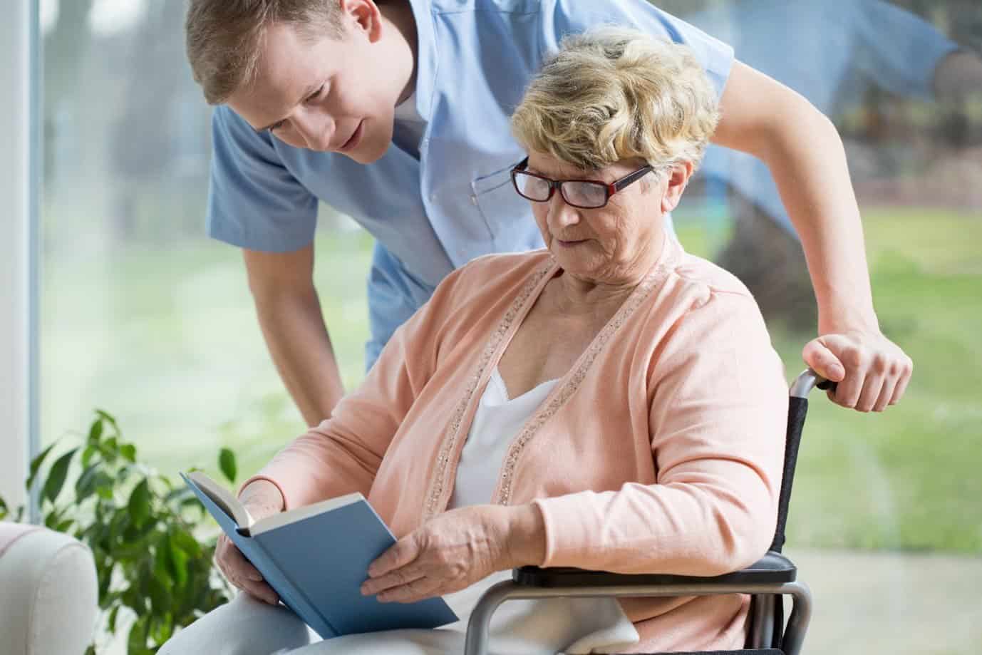 Male assisting elderly lady in wheelchair