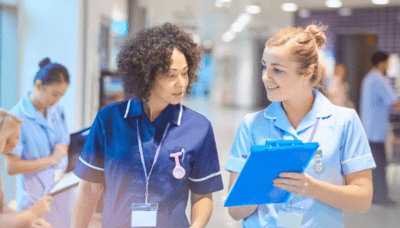 Two female healthcare works look over clipboard